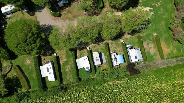 An aerial drone view reveals a charming Tuscan agriturismo nestled among vibrant sunflower fields and vast farmland. The property features a swimming pool and an organized camperstop for motorhomes in