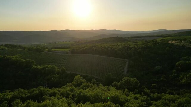 An aerial sunset panorama captures a historic Tuscan agriturismo and village. Surrounded by vast olive groves and vineyards, the scene features a camperstop with several motorhomes, a swimming pool