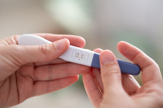 Close-up home pregnancy test in hands showing two lines as positive result. Concept of pregnancy, fertility, conception, family planning, motherhood, childbirth, prenatal care and baby anticipation.