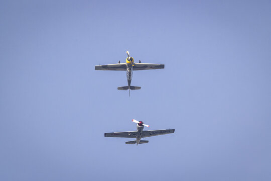 View of two vintage propeller aircraft flying in formation against a clear blue sky over La Spezia, Liguria, Italy.