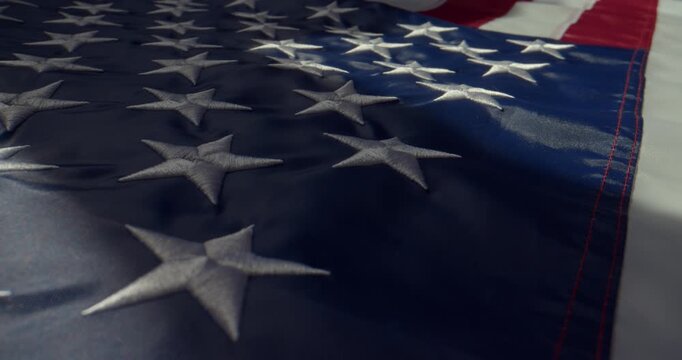 Close-up cinematic shot of the United States flag lying on a horizontal surface under directional local light. Slow push-in camera movement captured with a probe lens and slider.