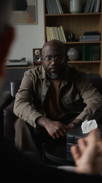 Vertical shot of African American man talking with psychotherapist during psychological therapy session. Footage fits mental healthcare commercials and counseling advertising