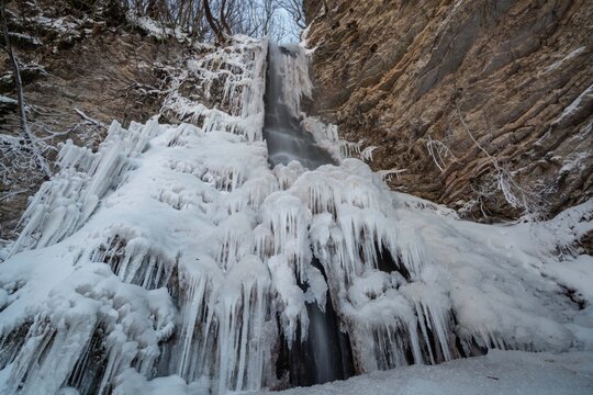 View of Cascate del Pisciatore featuring massive icicles and frozen water cascading down rocky cliffs in winter in Castelsantangelo sul Nera, Marche, Italy.