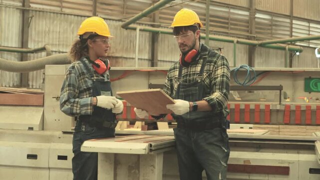 Workers safety gear ensure maximum safety operating the machinery : Male and female carpenter operate wood cutting machinery design furniture plywood factory manufactures various wood products.