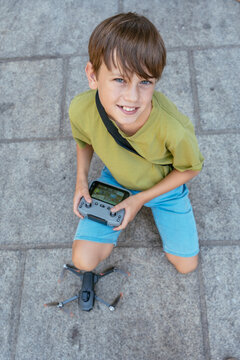 Vertical portrait of tech savvy young boy operating camera drone outdoors during summer vacation