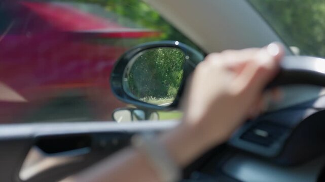 Side mirror reflection while driving slow motion close up transition pulling focus to the hand on steering wheel