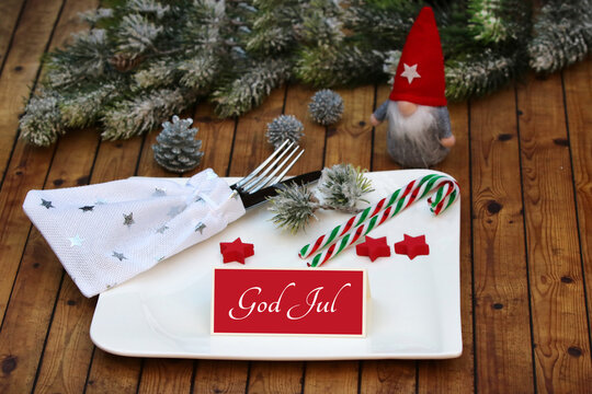 Scandinavian Christmas table decoration featuring a gnome, a candy cane, and a greeting card reading "God Jul."