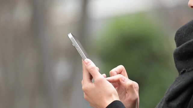冬の屋外でスマートフォンを操作する女性の手元