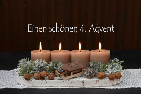 Rustikales Adventsgesteck mit vier brennenden Kerze, Zweigen und Holzschlitten zum 4. Advent.