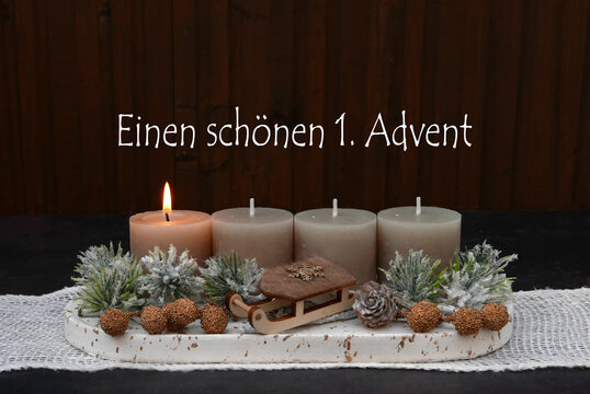 Rustikales Adventsgesteck mit einer brennenden Kerze ,Zweigen und Holzschlitten zum 1. Advent.