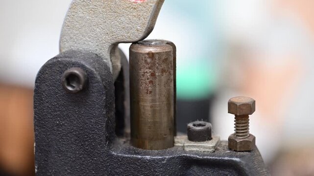 革細工でホックを取り付けるハンドプレス機のクローズアップ