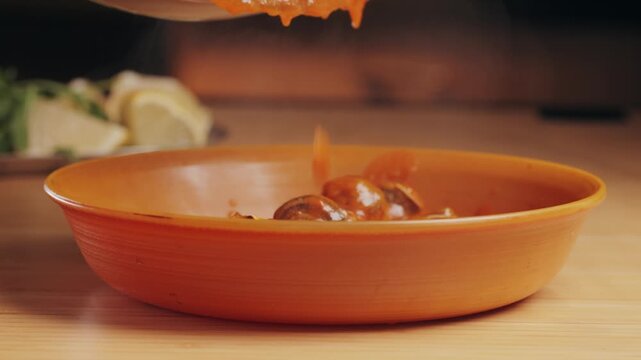 French snails, Close up of traditional spanish tapas - the boiled snails in tomato sauce with garlic and chili in black iron pan