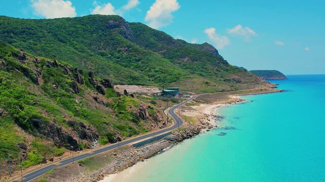 Drone orbit around winding coastal road and emerald sea in Con Dao
