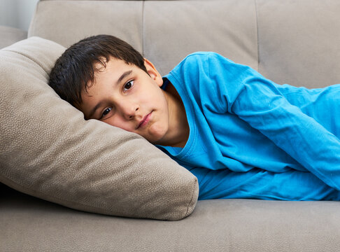 Mental health child concept. Sad kid is tired on sofa, thoughtful and depressed at home. Depressed unhappy child stressed with anxiety suffer frustration. Disappointed foster boy. Existential crisis.