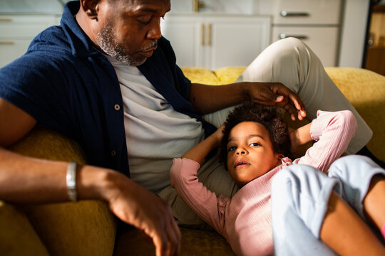 Man comforting child resting on his lap at home