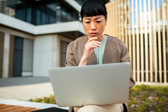 Concerned woman working on laptop outside office