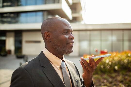 Businessman using voice command on smartphone outdoors