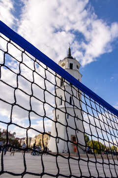 View of the historic Vilnius Cathedral Bell Tower seen through a sports net in the city square, with a blue sky and clouds in the background in Vilnius, Vilnius County, Lithuania.