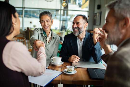 Business colleagues shake hands at coffee shop meeting
