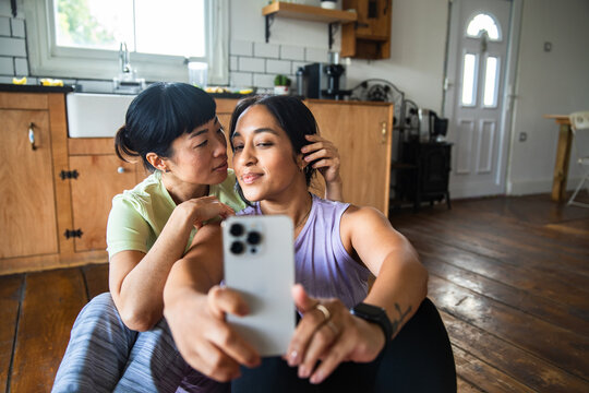 Two women taking a playful selfie on the kitchen floor