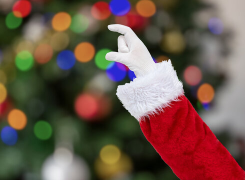 Santa Claus hand holding some like a blank object at home with christmas tree