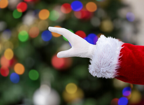 Shot of an Santa Claus hand holding some like a blank object at home with christmas tree