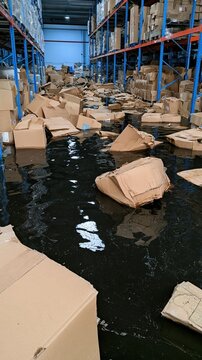 Warehouse boxes waterlogged and scattered across flooded aisle