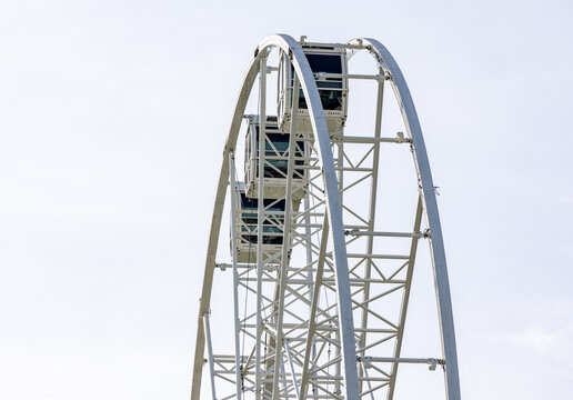 View of the white metal structure and passenger cabins of a Ferris wheel against a bright sky in Kaunas, Kaunas County, Lithuania.