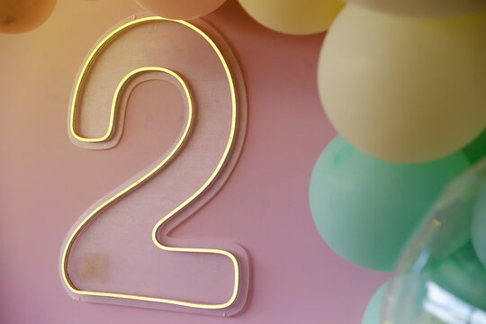 LED neon luminous sign in the shape of number two with colorful balloons