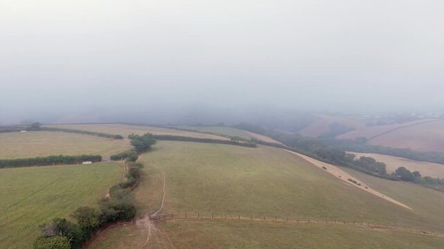Aerial view of foggy farmland along the edge of a valley in rural Cornwall, Looe, England, United Kingdom.