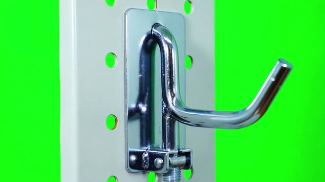 Metallic silver pegboard hook rotating slowly on a bright green screen background for easy keying and visualization