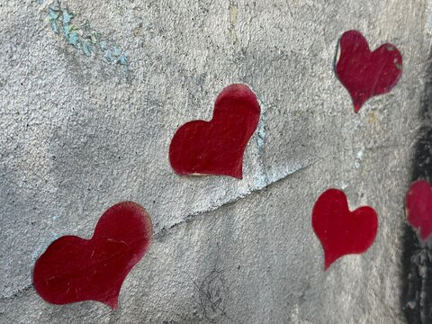 Spray painted red hearts graffiti on weathered concrete wall street art close up