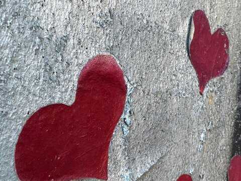 Spray painted red hearts graffiti on weathered concrete wall street art close up