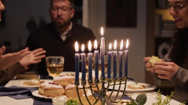 Caucasian family dining and toasting with wine behind lit menorah during Hanukkah celebration. Footage suitable for Jewish cultural campaigns and seasonal holiday marketing