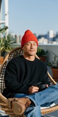 Fototapeta premium Man relaxing on balcony with coffee cup and red beanie for lifestyle banner background and social media wellness content