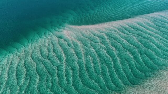 Aerial view of intricate sand ripples beneath clear turquoise water at Amity Point, Queensland, Australia.
