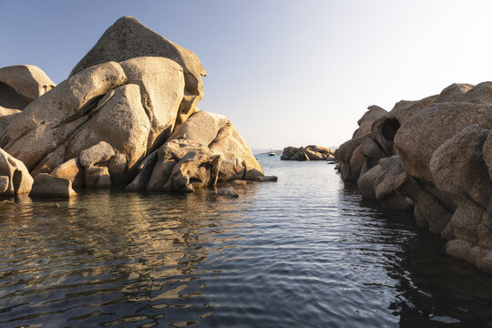 View of Spiaggia Testa del Polpo with its characteristic granite rock formations rising from the clear turquoise water in La Maddalena, Sardinia, Italy.