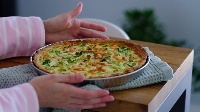 Thanksgiving holiday cooking concept video featuring a person holding a freshly baked traditional quiche or pie on a kitchen table, representing autumn celebrations, family dinner preparation, and gra