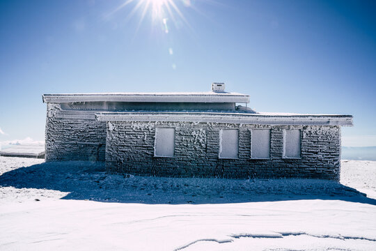View of Golyam Kademliya Shelter covered in thick frost and ice under a clear blue sky in the snowy mountains, Stara Zagora, Bulgaria.