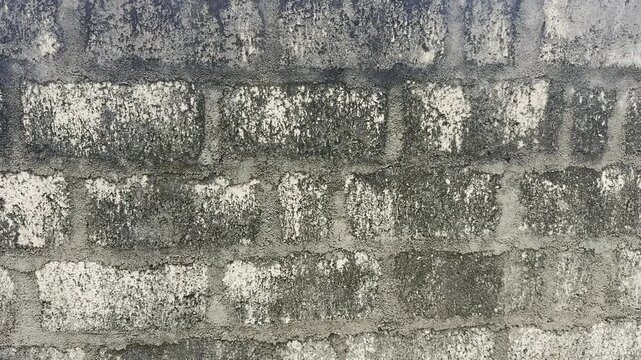 dirty weathered cement block wall background, rough concrete surface with dark stains and grunge pattern in close-up, industrial construction in slow motion taken in 60fps