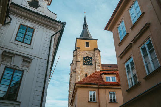 View of the historic clock tower rising above traditional buildings with terracotta roofs in the old town of Prague, Prague, Czechia.