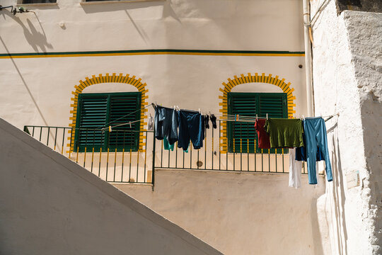 View of laundry hanging on a clothesline in front of a building with green shutters and yellow trim in Atrani, Campania, Italy.