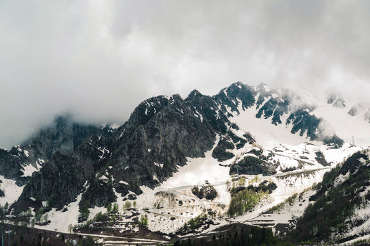Rugged rocky ridge with snowfields under dark storm clouds, dramatic alpine landscape