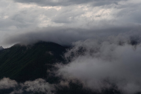 Dark storm clouds rolling over forested mountain, bad weather approaching in highlands