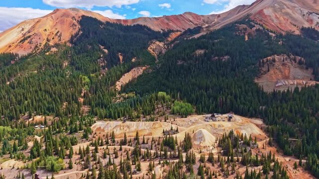 Panoramic aerial view shows historic wooden Yankee Girl Mine headframe amid colorful Red Mountains near Ironton along Million Dollar Highway Colorado