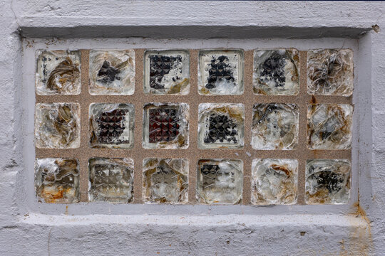 Broken and shattered glass blocks in an old building wall