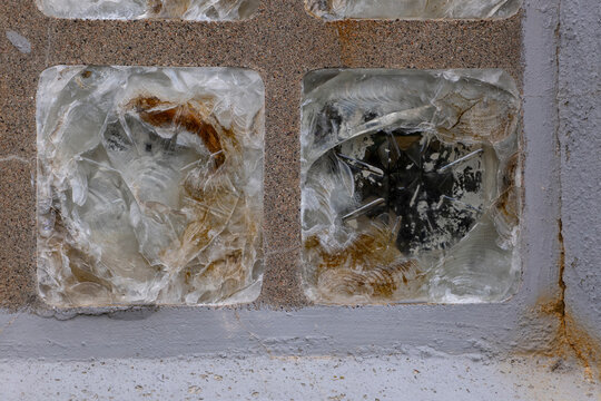 Broken and shattered glass blocks in an old building wall