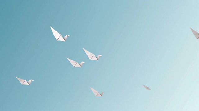 A flock of delicate origami paper cranes gracefully glides across a serene pale blue sky, conveying a sense of freedom, peace, and artistic handmade creation