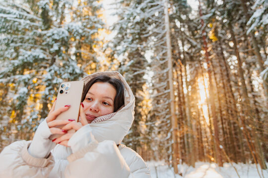 Young Woman Using Phone in Snowy Winter Forest