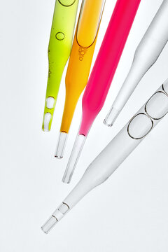 Laboratory Glass Pipettes with Colorful Liquids on Light Background.